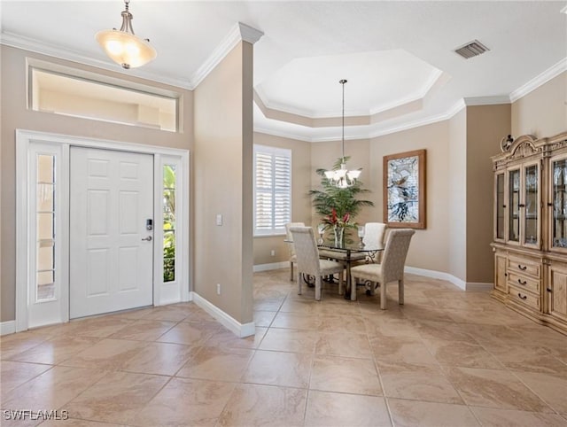 foyer with a notable chandelier, ornamental molding, and a tray ceiling