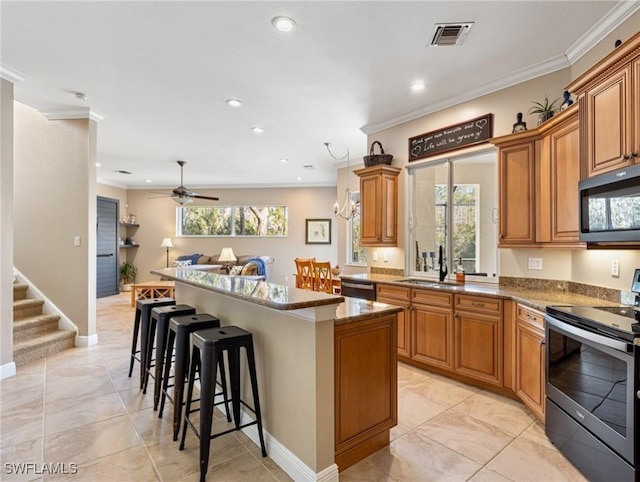 kitchen featuring ceiling fan, a center island, sink, stainless steel appliances, and a kitchen breakfast bar