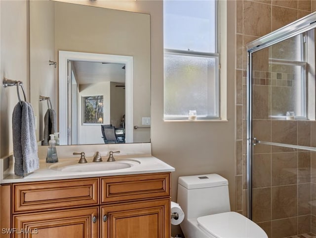 bathroom with vanity, a shower with door, toilet, and a wealth of natural light