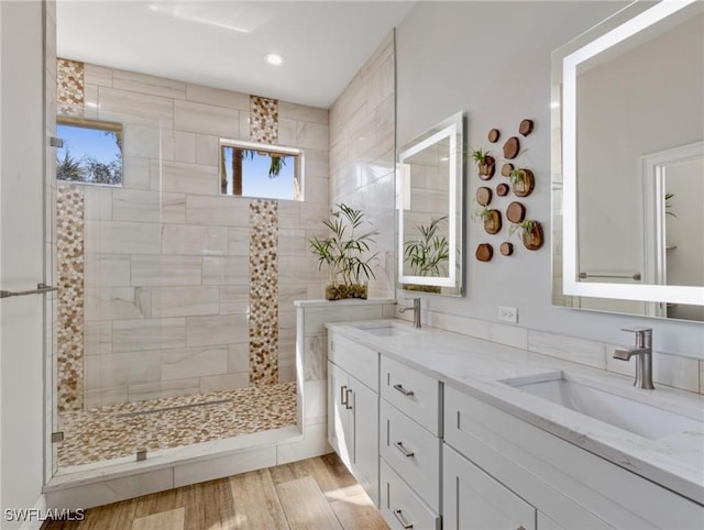 bathroom with wood-type flooring, vanity, and a tile shower