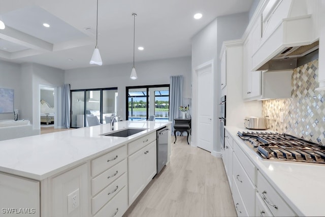 kitchen with sink, pendant lighting, a center island with sink, custom exhaust hood, and appliances with stainless steel finishes