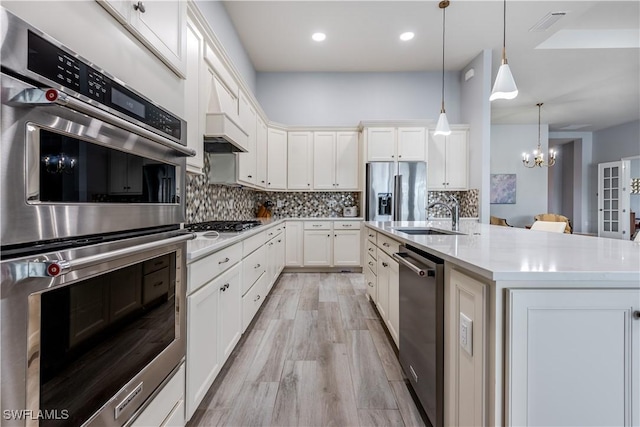 kitchen with pendant lighting, a center island with sink, sink, a notable chandelier, and stainless steel appliances