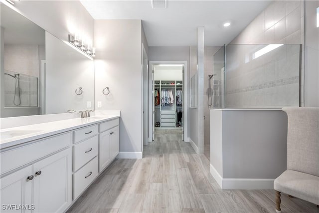 bathroom with hardwood / wood-style floors, vanity, and a shower with shower door