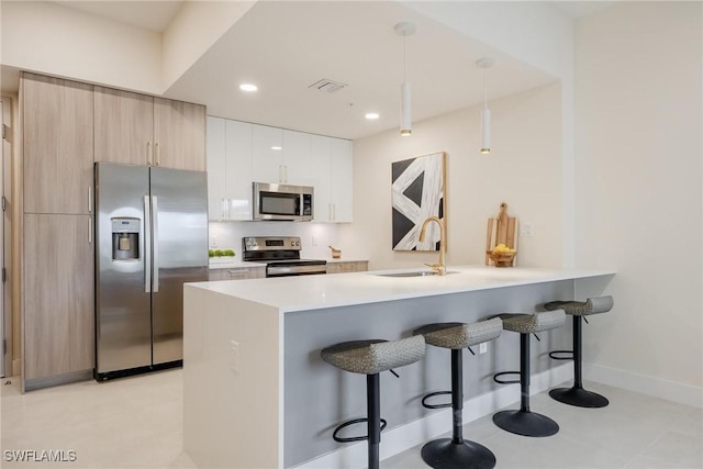 kitchen featuring stainless steel appliances, hanging light fixtures, a breakfast bar area, and sink