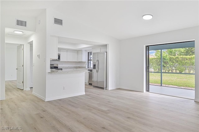 kitchen with white cabinets, stainless steel appliances, kitchen peninsula, light wood-type flooring, and light stone counters