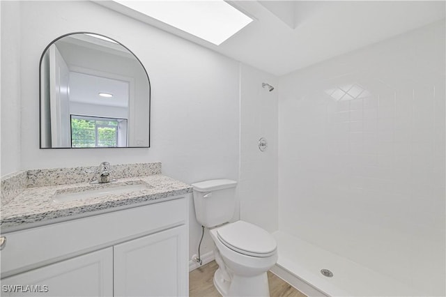 bathroom with wood-type flooring, vanity, a skylight, a shower, and toilet