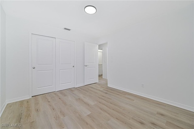 unfurnished bedroom featuring light wood-type flooring and a closet