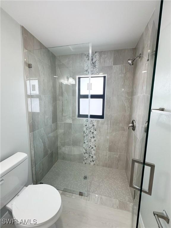 bathroom with toilet and a shower with shower door