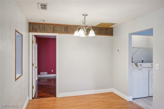 unfurnished dining area with a chandelier, washer and dryer, and hardwood / wood-style flooring