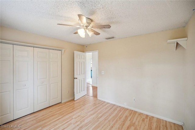 unfurnished bedroom with ceiling fan, a closet, a textured ceiling, and light wood-type flooring