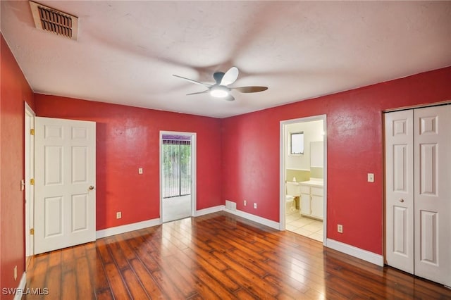 unfurnished bedroom featuring hardwood / wood-style flooring, ensuite bathroom, and ceiling fan