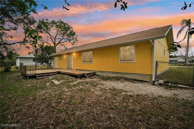 back house at dusk featuring a deck