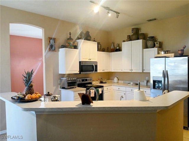 kitchen with white cabinets, stainless steel appliances, track lighting, and a center island with sink