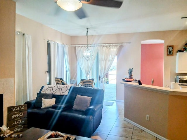 tiled living room with ceiling fan with notable chandelier