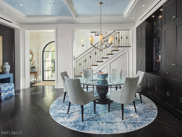 dining space featuring a raised ceiling, crown molding, and a notable chandelier