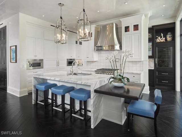 kitchen featuring dark parquet flooring, a large island, wall chimney exhaust hood, oven, and white cabinets