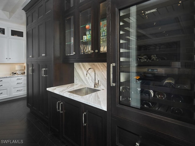 bar with backsplash, light stone countertops, sink, and white cabinets