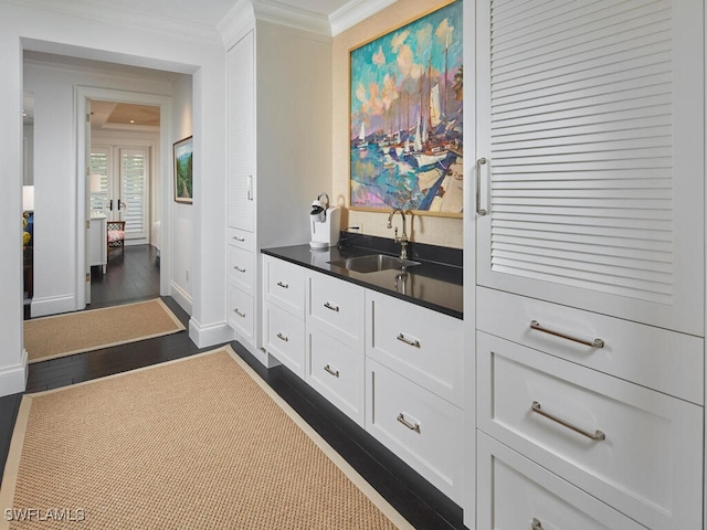 bar with crown molding, dark hardwood / wood-style flooring, white cabinetry, and sink