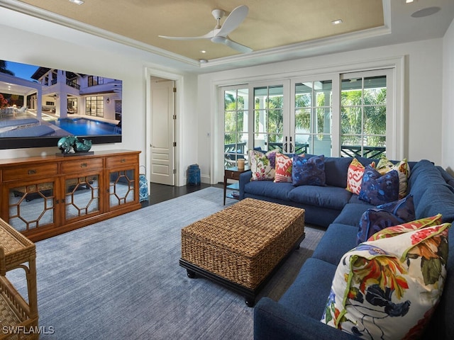 living room featuring a raised ceiling, ceiling fan, french doors, and dark wood-type flooring