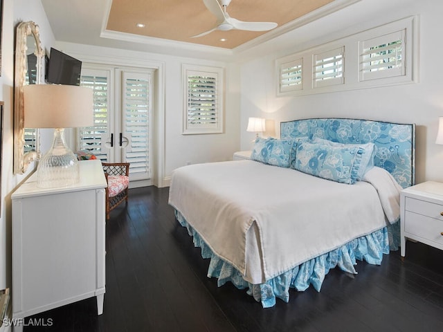 bedroom featuring ceiling fan, a raised ceiling, dark wood-type flooring, and crown molding