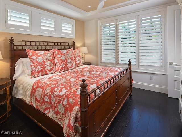 bedroom with dark hardwood / wood-style flooring, a tray ceiling, multiple windows, and crown molding