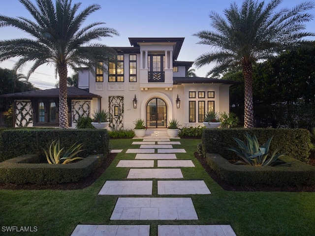 view of front of home with a yard, french doors, and a balcony