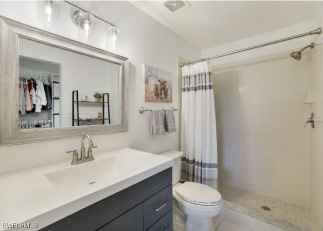 bathroom with a shower with curtain, vanity, toilet, and tile patterned floors