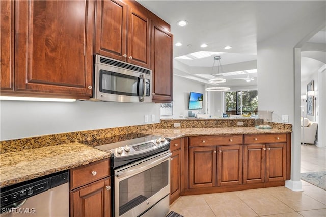 kitchen featuring light stone counters, light tile patterned floors, kitchen peninsula, and appliances with stainless steel finishes