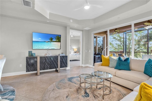 living room featuring plenty of natural light, light tile patterned flooring, and a tray ceiling