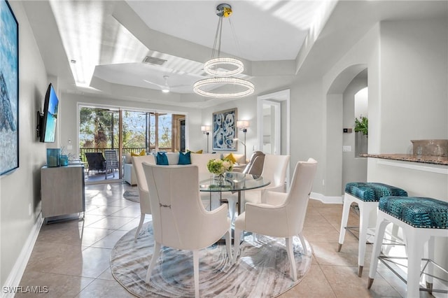 dining area with a chandelier, light tile patterned floors, and a tray ceiling