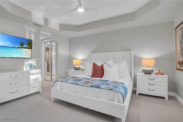 carpeted bedroom featuring a raised ceiling and ceiling fan