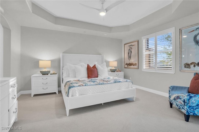 carpeted bedroom with a tray ceiling and ceiling fan