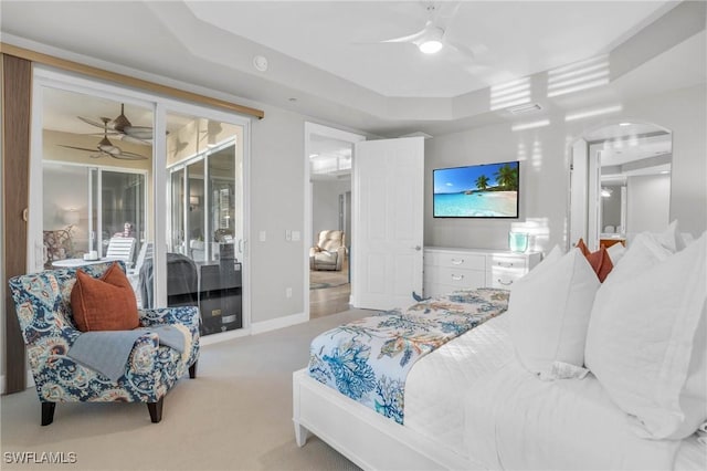 carpeted bedroom featuring a raised ceiling, ceiling fan, and access to exterior