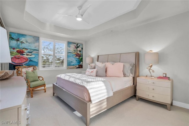 bedroom with a raised ceiling, ceiling fan, and light colored carpet