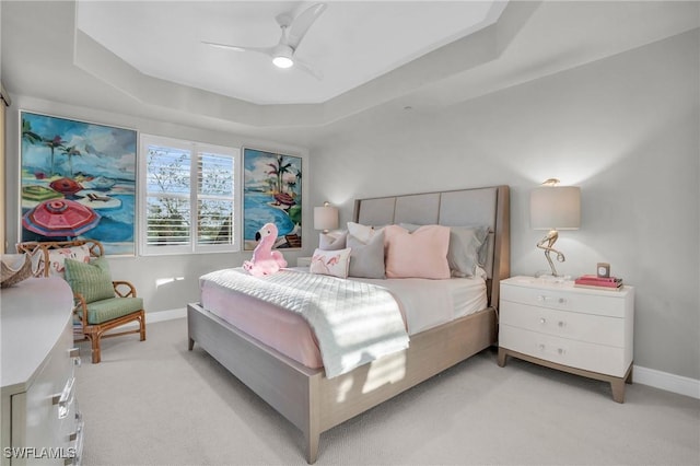 carpeted bedroom with a raised ceiling and ceiling fan