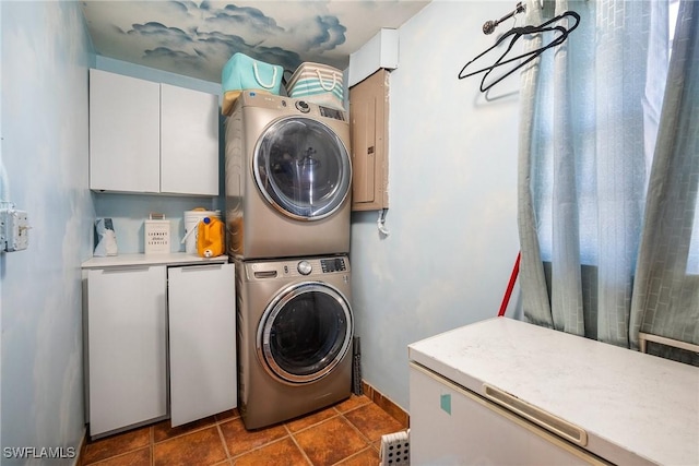 laundry room featuring cabinets and stacked washer / drying machine