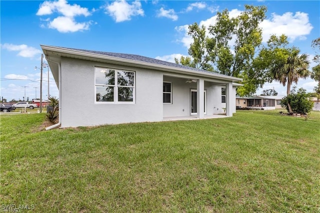 back of property featuring a lawn and ceiling fan