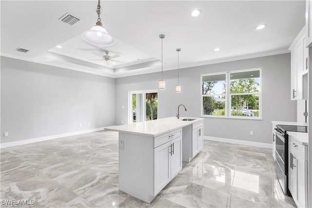 kitchen featuring a center island with sink, white cabinets, a raised ceiling, sink, and appliances with stainless steel finishes