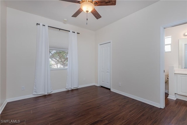 unfurnished bedroom featuring multiple windows, ensuite bathroom, ceiling fan, and dark hardwood / wood-style flooring