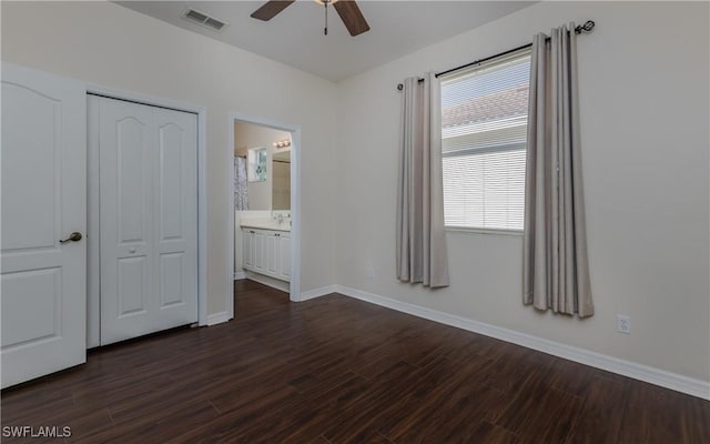 unfurnished bedroom featuring a closet, ceiling fan, ensuite bathroom, and multiple windows