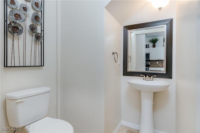 bathroom featuring sink, toilet, and tasteful backsplash