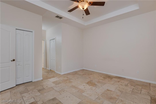 unfurnished bedroom featuring ceiling fan and a tray ceiling