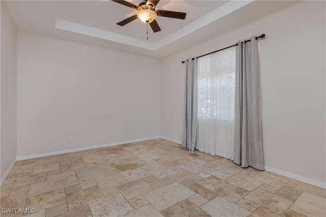 unfurnished room featuring ceiling fan and a raised ceiling