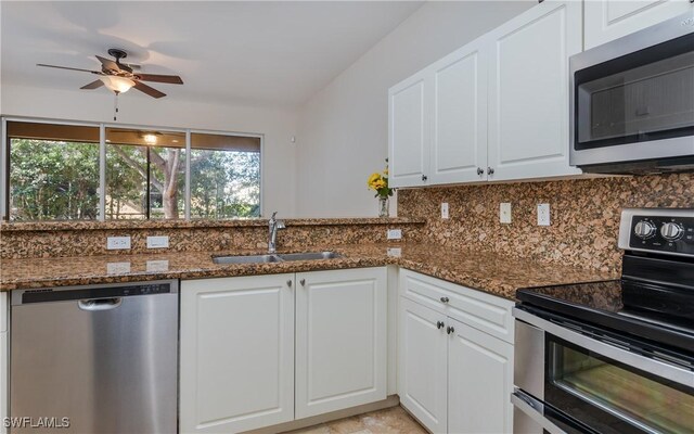 kitchen featuring sink, white cabinets, stainless steel appliances, and dark stone counters