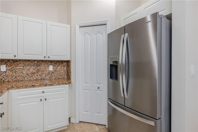 kitchen with white cabinetry, stainless steel fridge with ice dispenser, dark stone counters, and tasteful backsplash