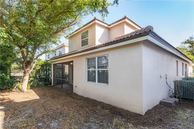 view of property exterior with cooling unit and a sunroom