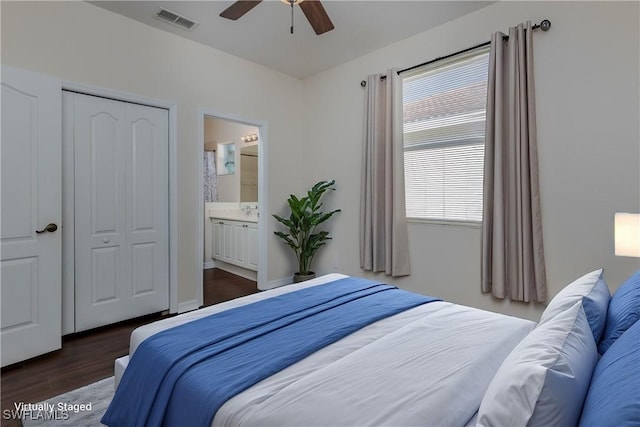 bedroom featuring sink, ceiling fan, ensuite bathroom, dark hardwood / wood-style flooring, and a closet