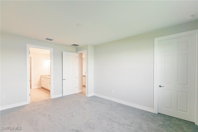 unfurnished bedroom with light colored carpet and ensuite bath