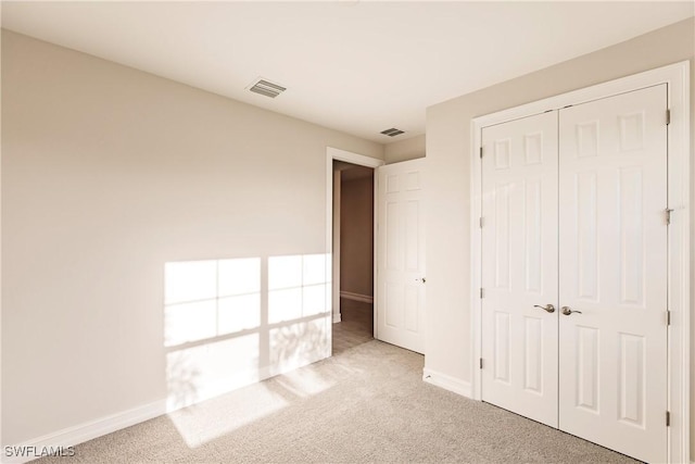 unfurnished bedroom with a closet and light colored carpet