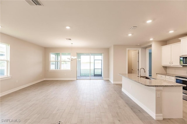 kitchen with a kitchen island with sink, white cabinets, sink, light hardwood / wood-style floors, and stainless steel appliances